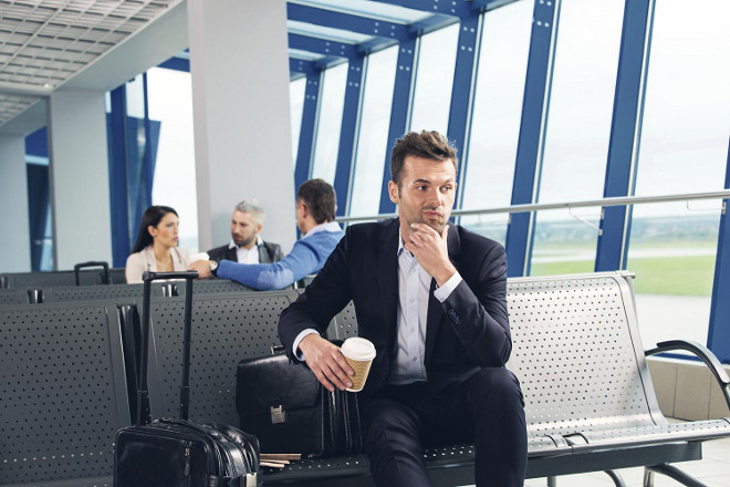 Businessman Seated in Airport Boarding Gate with Briefcase and Coffee